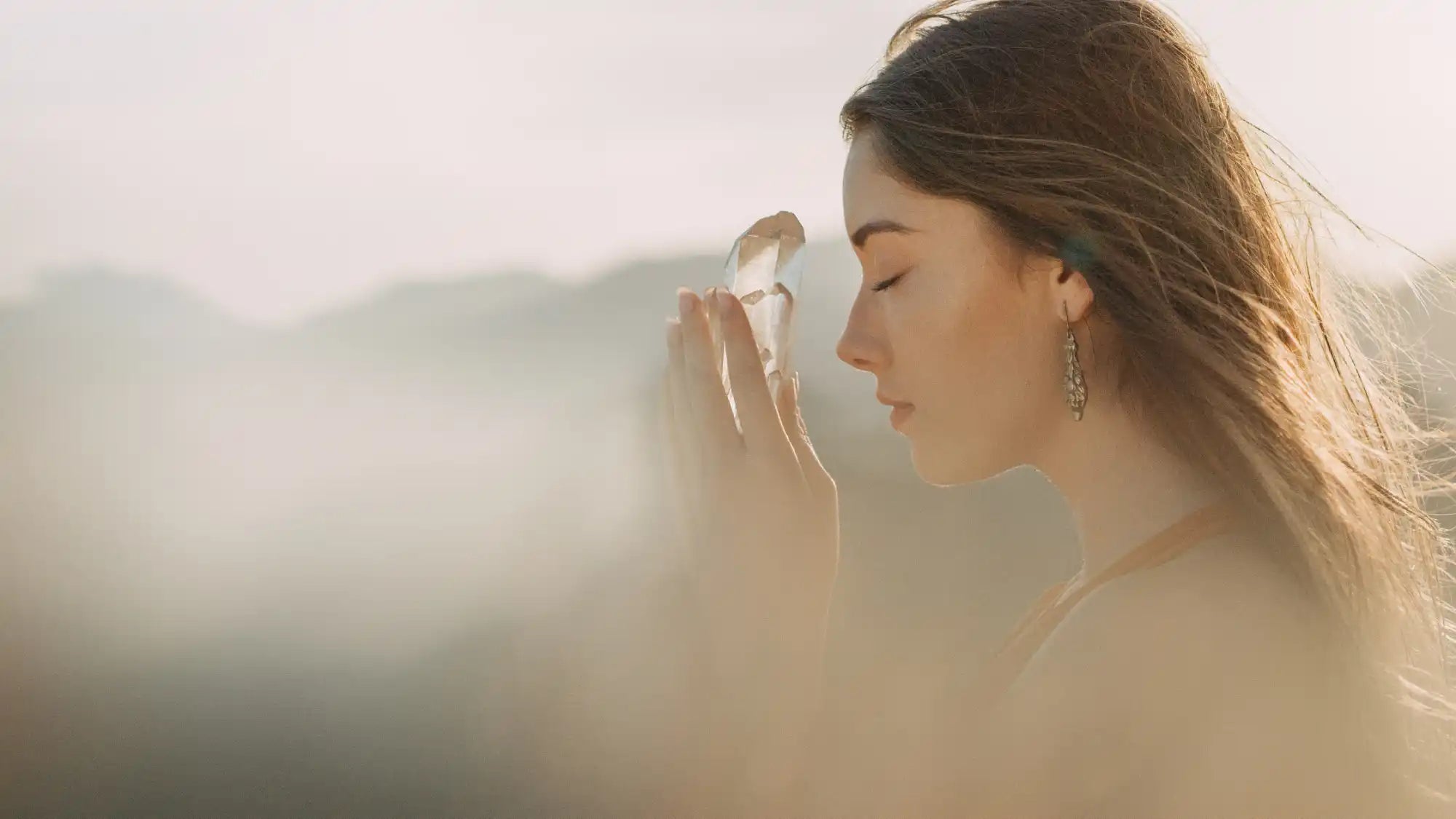 A young woman holding a clear crystal in her hands.
